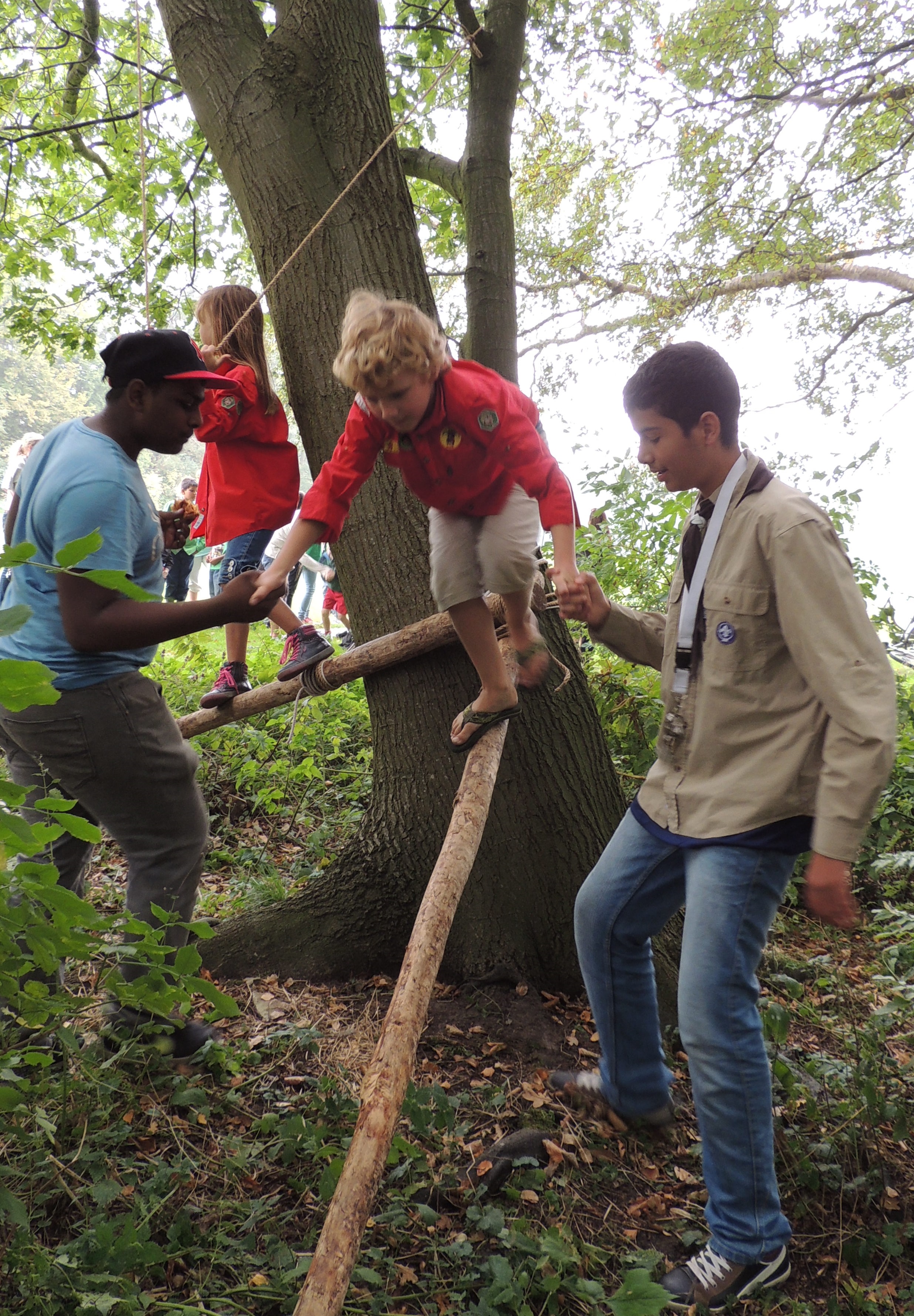 oudere scouts helpen de jongste over de hindernis